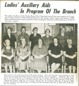 Black and white newspaper article titled “Ladies’ Auxiliary Aids In Program Of The Branch” and a 50-word text that describes the photograph, featuring 10 women, five of whom are seated in the front row and five others standing behind them (their names are indicated below the photograph).