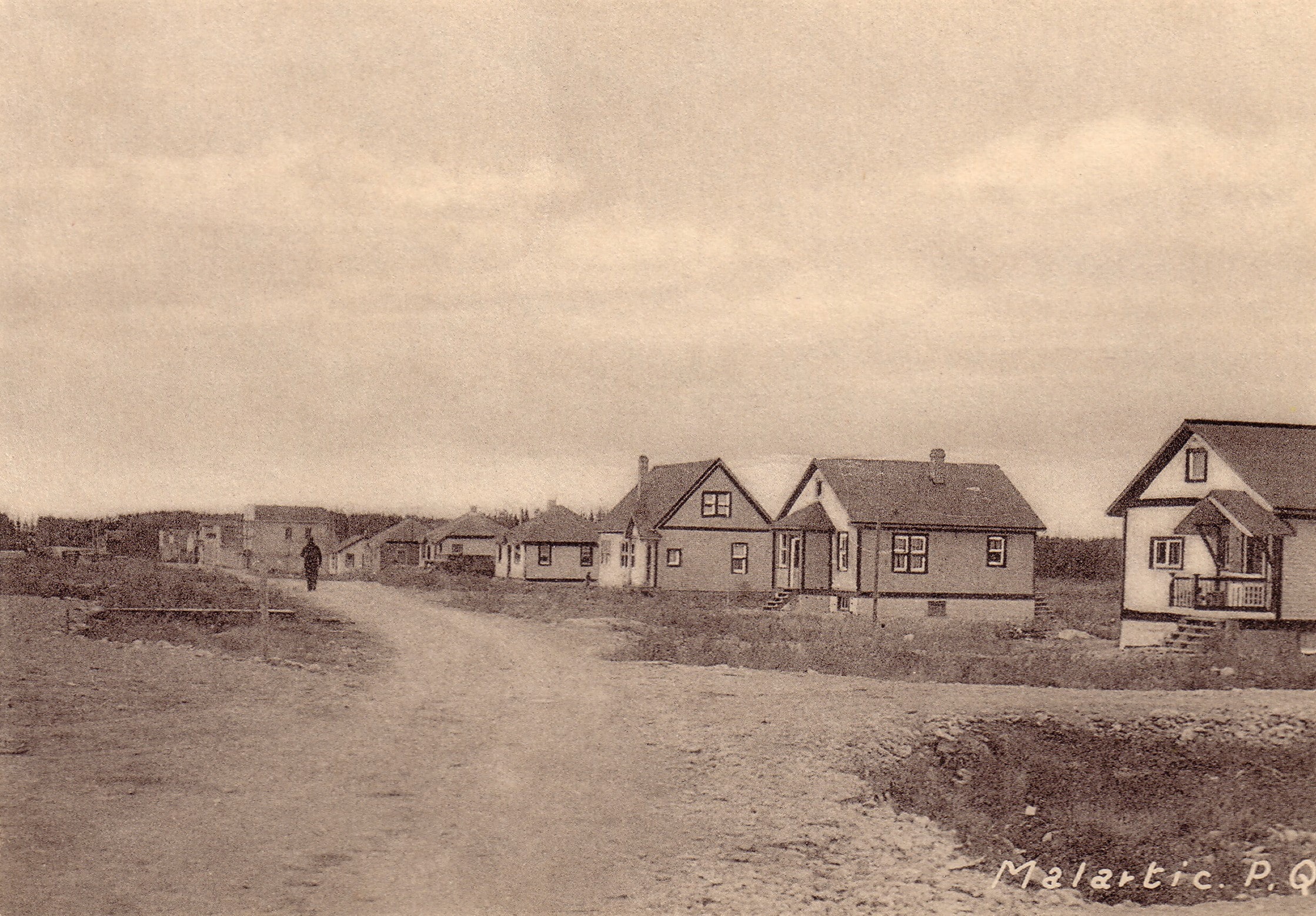 Sepia photograph of several residences lined up on one side of an unpaved street. In the centre, a man is walking. The inscription at the bottom right reads, "Malartic. P. Q.".