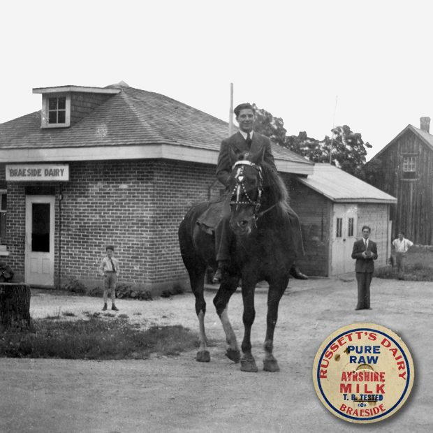 A young man sits on a horse in front of a small building with a sign for the Braeside Dairy over the door. A small boy and two other men look towards the camera. An insert appears in the lower right corner showing a bottle top for Russett's Dairy.