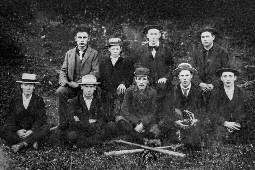 Two rows of baseball players pose for a team photograph in front of crossed wooden bats.