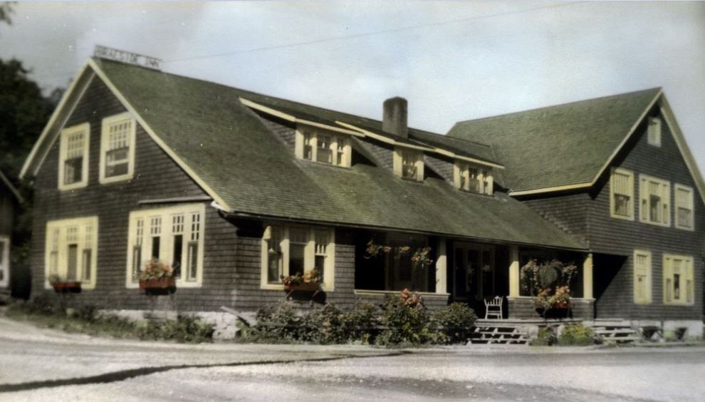 A colour tinted post card shows a large inn with a covered porch and window boxes.