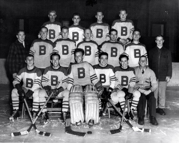 Hockey team photograph shows coaches players wearing white team jerseys with a large B on the front.