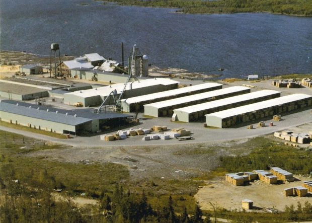 An aerial photograph shows Gillies Bros. mill site in summertime with log booms near shore.