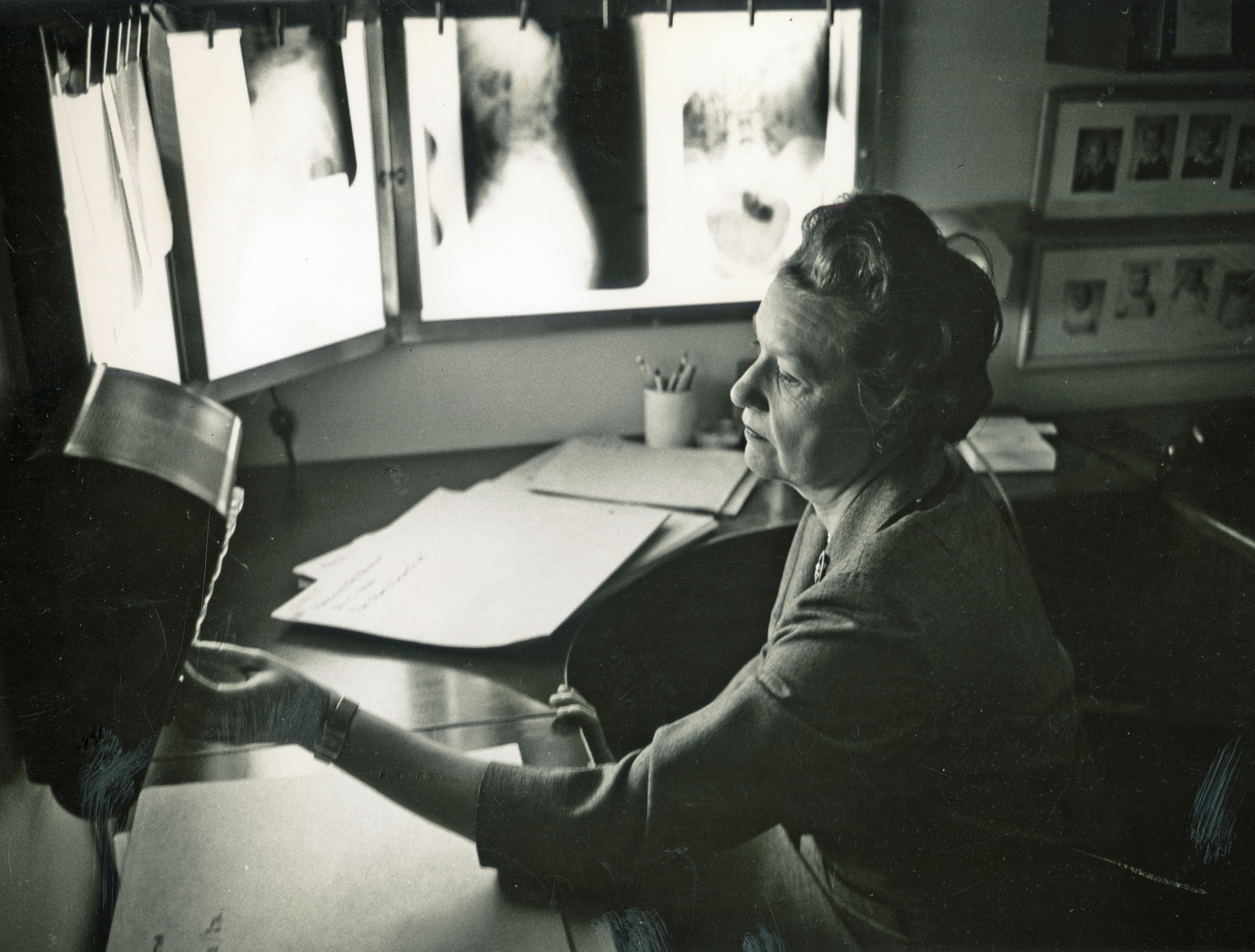 A black and white photo of a woman reviewing X-rays.