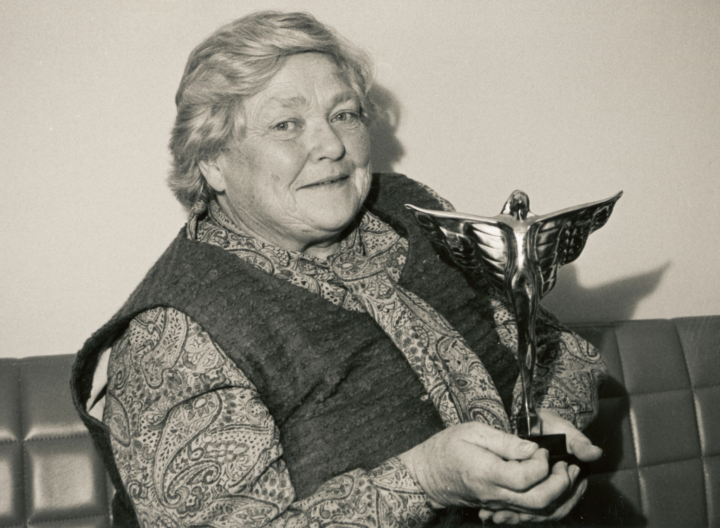 A woman holding a trophy, smiling.