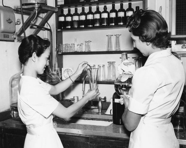A black and white photo of two young women working in a laboratory.