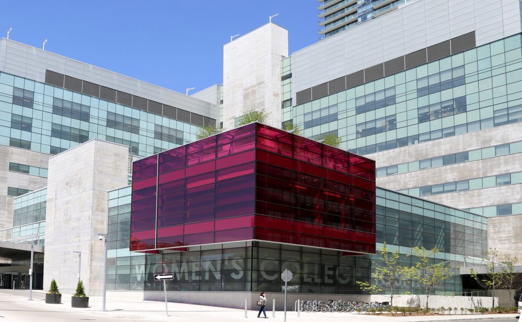 A coloured exterior photo of Women's College Hospital; the building features a large pink glass cube.