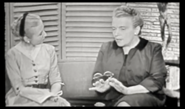 A frame from a black and white video of two women chatting.