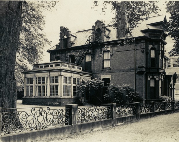 A large home from behind a wrought-iron rail.