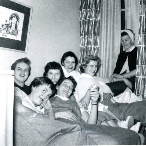 Seven young women are laughing and relaxing in casual clothing.