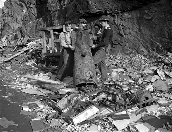 photo of men holding aft section of German torpedo that struck pier on Bell Island