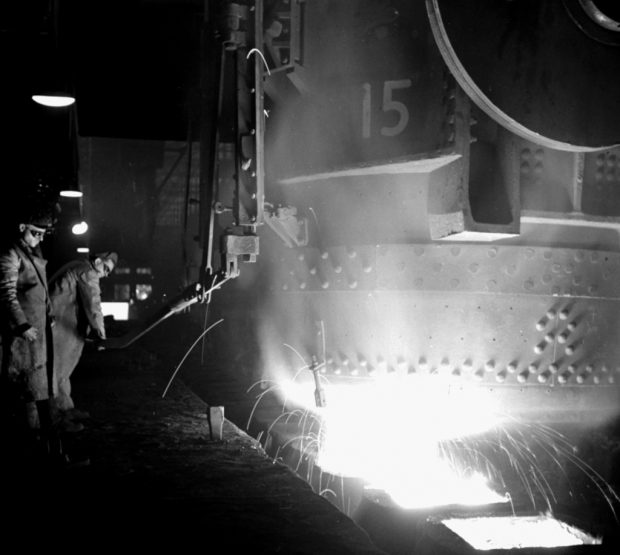 Two workers pouring molten steel in an industrial steel mill