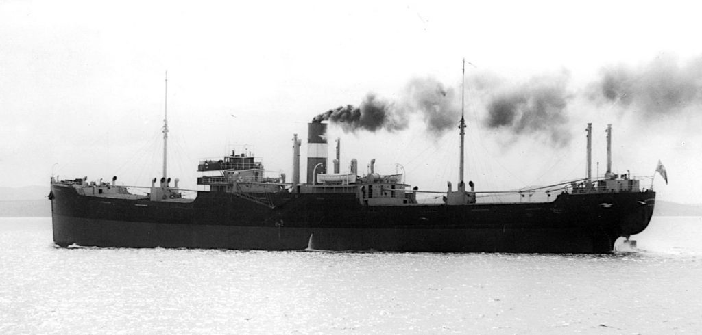 a large steel cargo ship at sea with a plume of coal smoke from the funnel