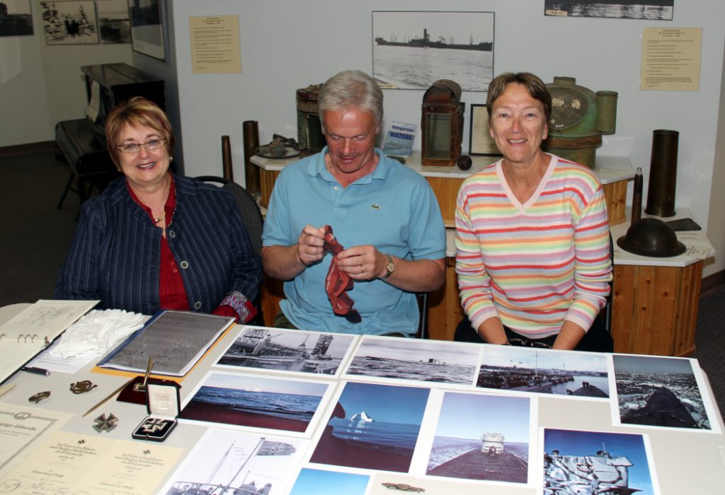 three people sitting at a table covered in photographs