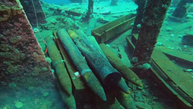 a dozen artillery shell on the deck of a submerged shipwreck