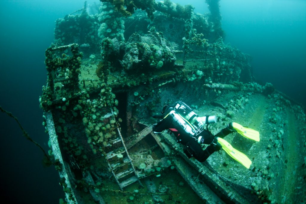 rebreather diver swimming over the deck of a large submerged shipwreck