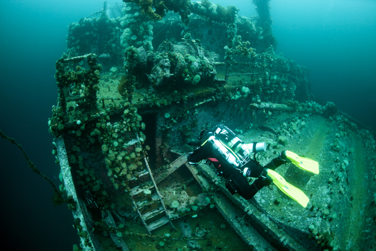 rebreather diver swimming over the deck of a large submerged shipwreck