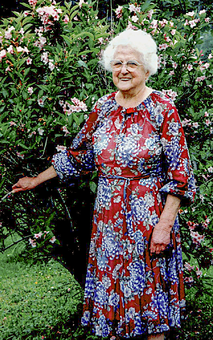 elderly woman in a print dress standing outside