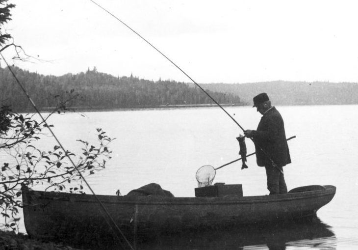 Black and white photo of fishermen in a steamboat on lac Édouard.