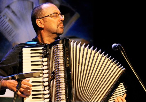 Colour photograph of Martin Bellemare standing and playing piano accordion, as he faces the audience with his eyes closed.