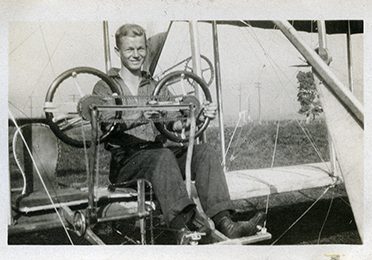 A man sitting in the pilot’s seat of a bi-plane.