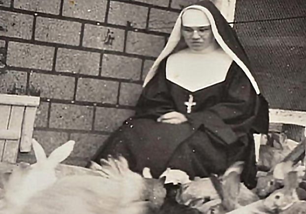 Black and white photo of a nun surrounded by rabbits.