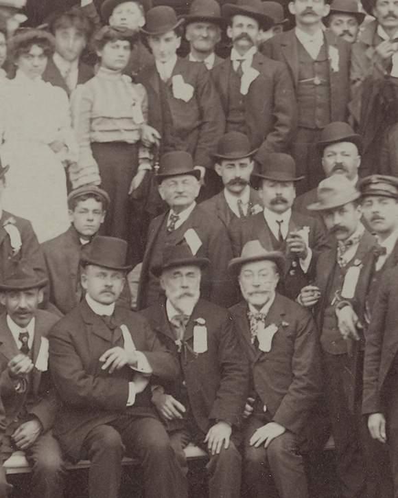 Sepia-tone photograph showing men and some women outside, in front of a paper mill.