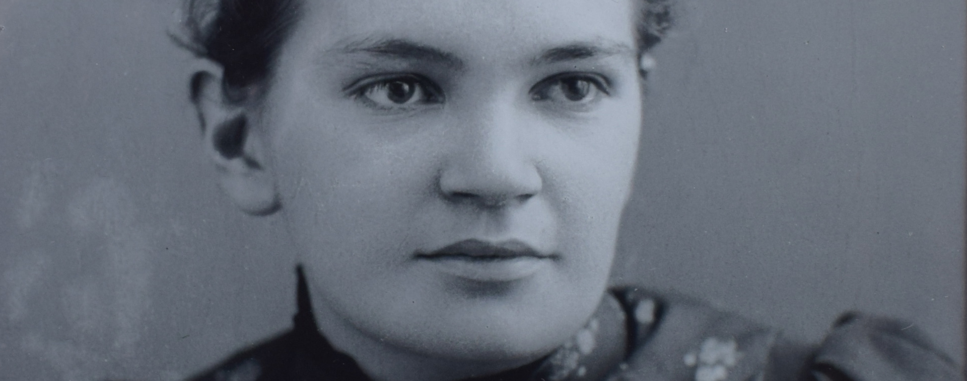 Photograph showing the face of Dr. Maude Elizabeth Abbott in a panoramic close-up. She is young and wears a flowered dress. Her gaze is piercing. She smiles peacefully. She is 22 years old.