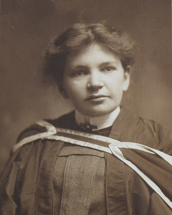 Black and white photograph of Maude Abbott as a young adult, from the waist up. She is wearing a graduation gown. Her dark hair is tied behind her head and she is looking slightly to her left.