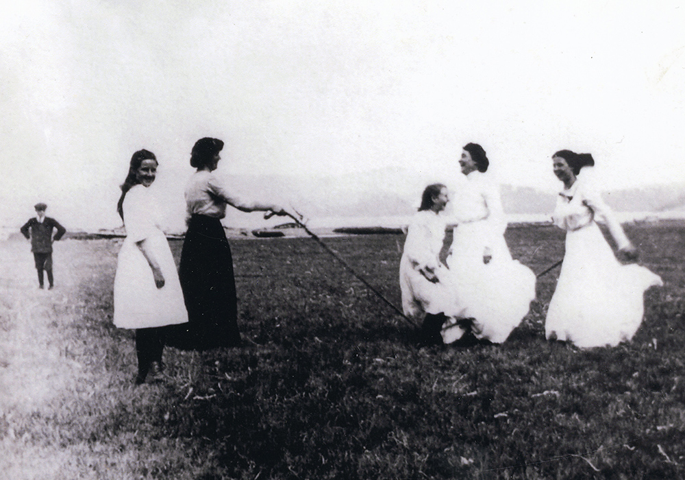 A black and white photograph of women skipping with a jump rope in a field.