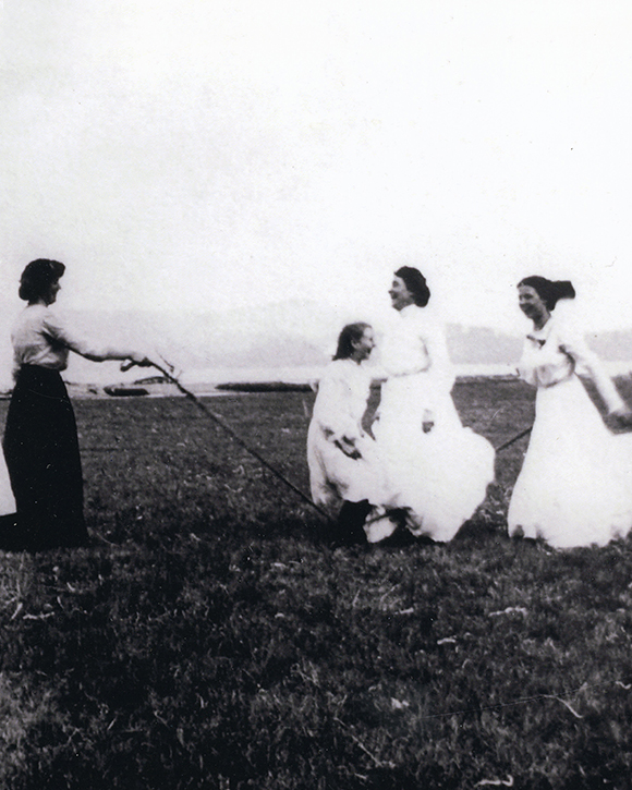 A black and white photograph of women skipping with a jump rope in a field.