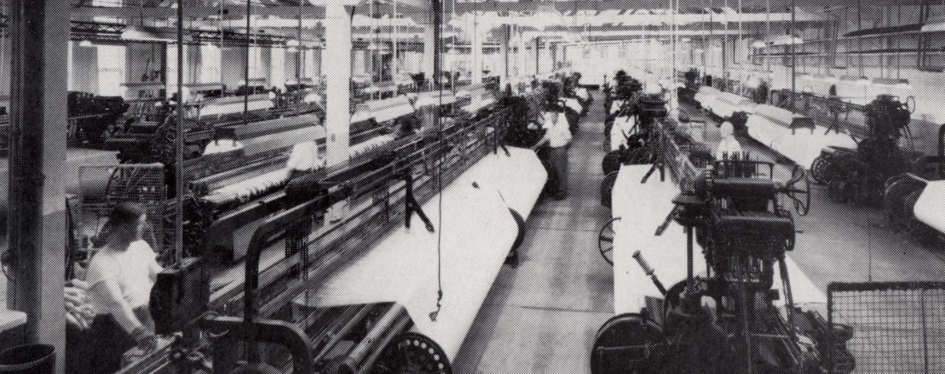 A factory floor with several rows of weaving machines.