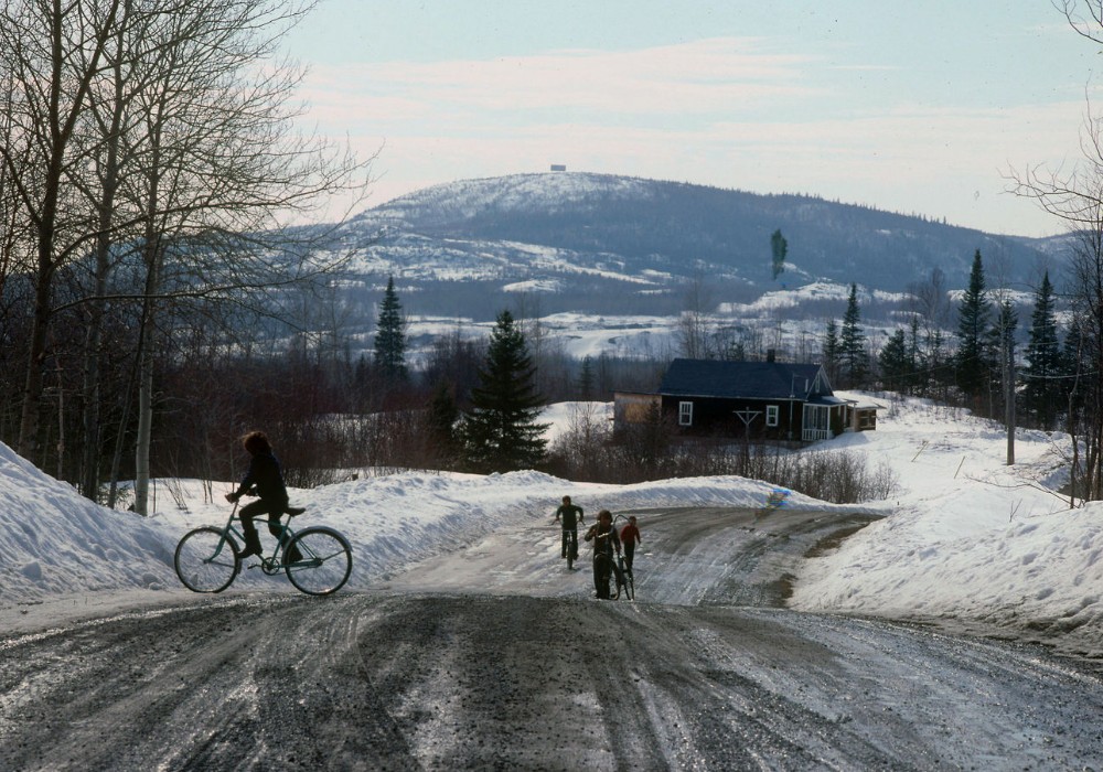 View of a landscape and a rural road in spring during the snow melt. Children riding their bikes.