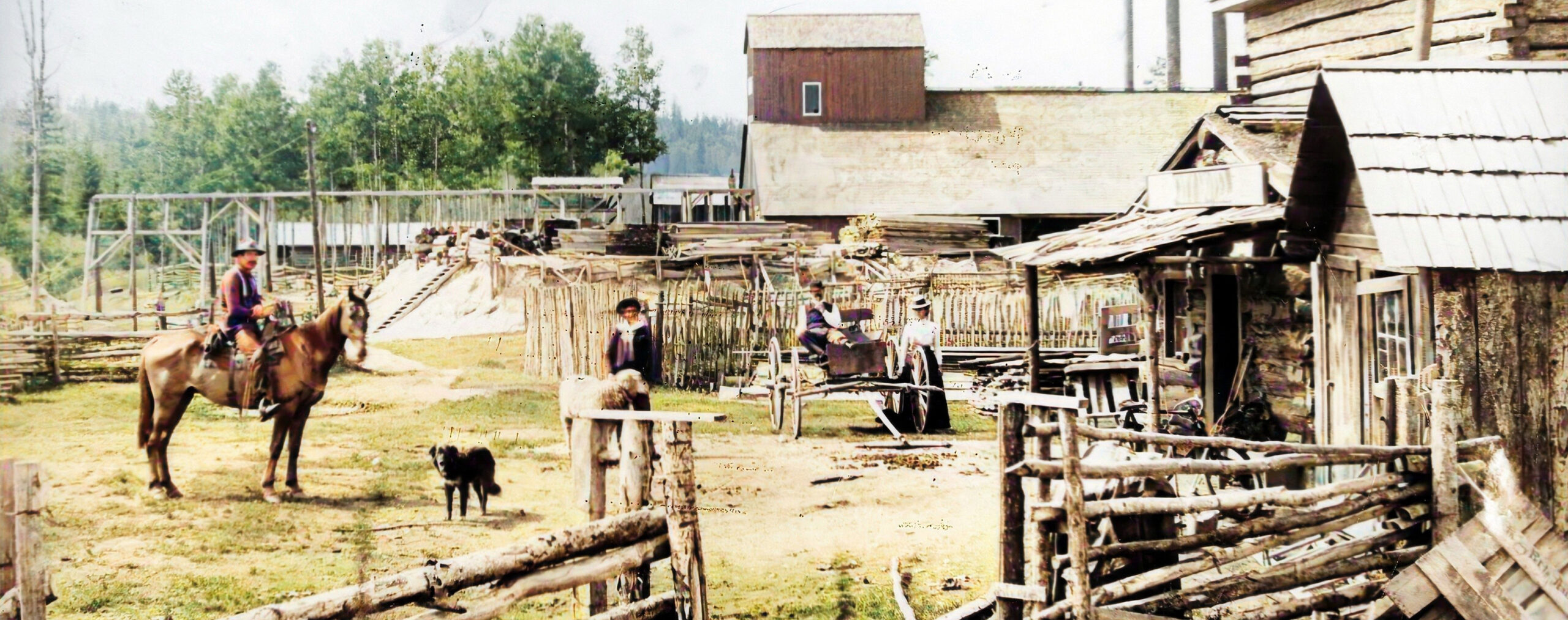 Man on horseback, dog and buggy in front of wooden buildings and fences
